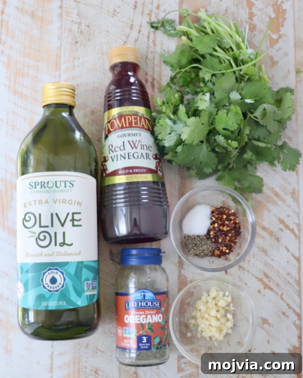 ingredients for cilantro chimichurri sauce on a white wood board