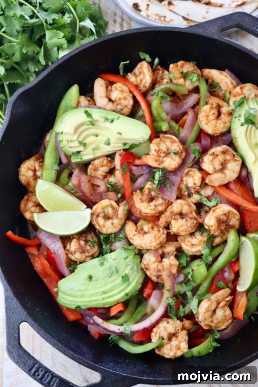 Sizzling Shrimp Fajita Feast 2 shrimp fajitas in a cast iron skillet topped with sliced avocado and lime wedges