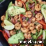 Sizzling Shrimp Fajita Feast 11 shrimp fajitas in a cast iron skillet topped with sliced avocado and lime wedges