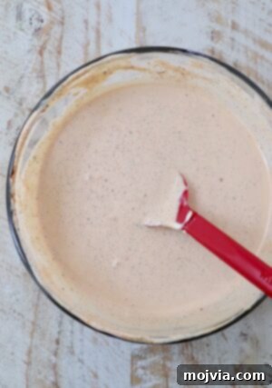 creamy Cajun sauce mixed together in a glass bowl with a red spatula