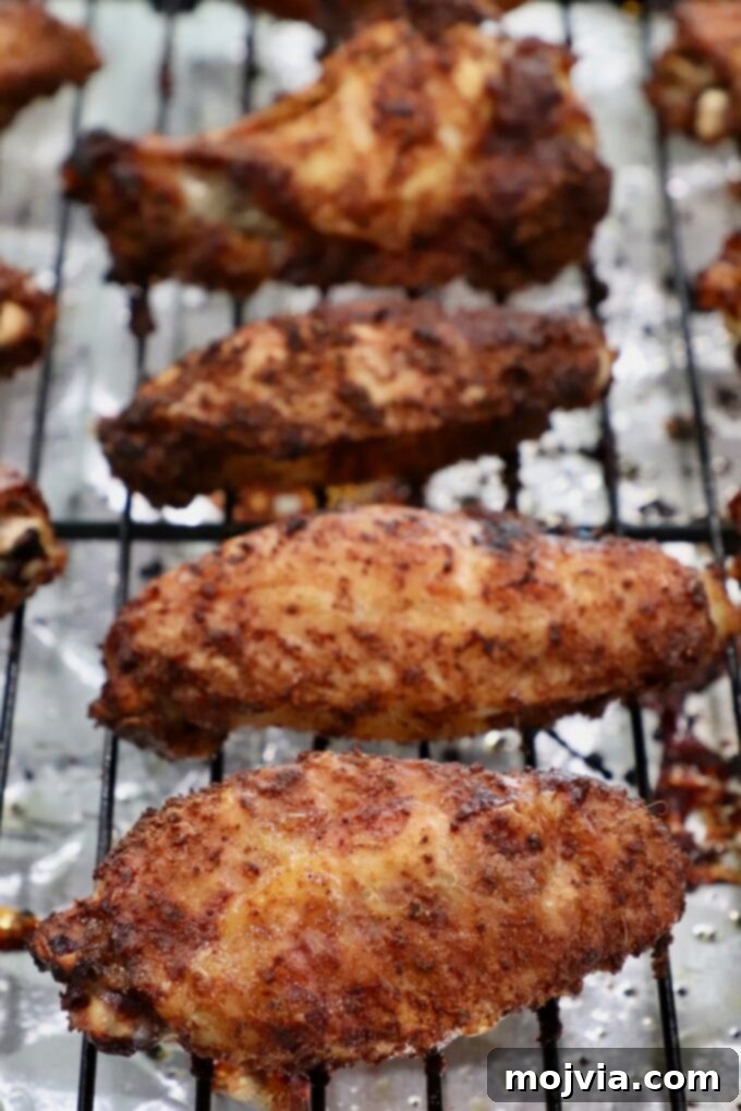 Crispy, golden-brown chicken wings, perfectly cooked and seasoned, resting on a wire rack over a baking sheet.