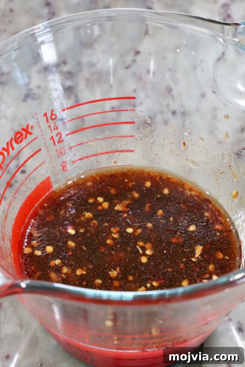 Sticky, Sweet, and Spicy General Tso Sauce 4 Homemade General Tso sauce perfectly mixed in a clear glass measuring cup, ready to be used.