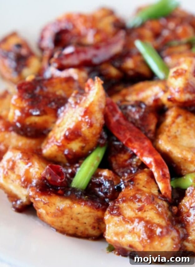 Sticky, Sweet, and Spicy General Tso Sauce 6 Classic General Tso chicken served on a plate, garnished with fresh red chilies and green scallions.