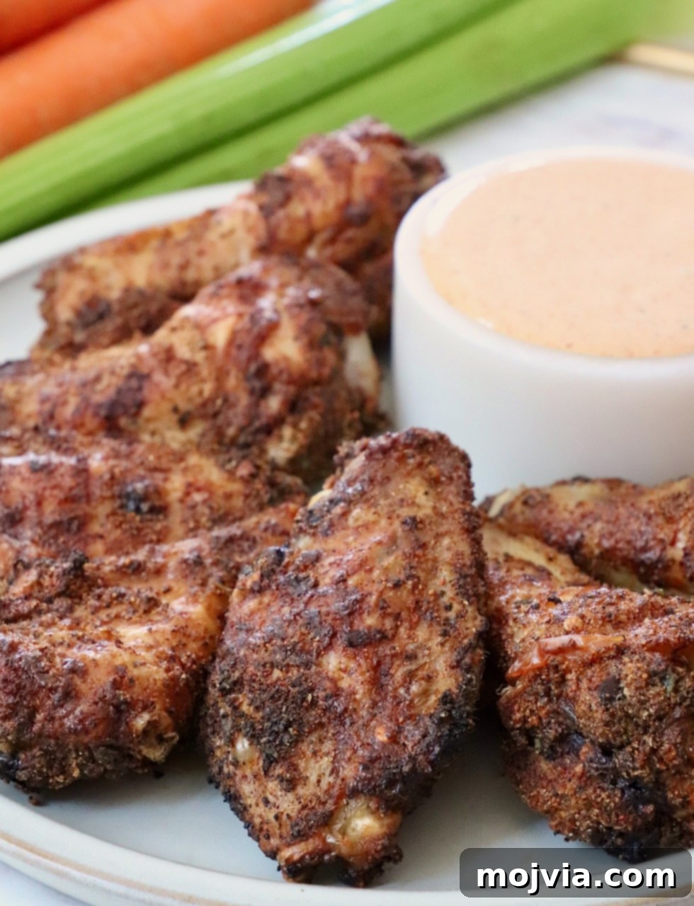seasoned baked chicken wings on a plate with a bowl of sauce