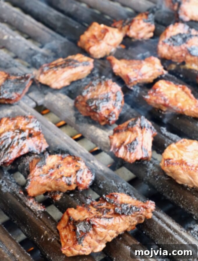 Grilled steak tips sizzling on the grill, developing a perfect char