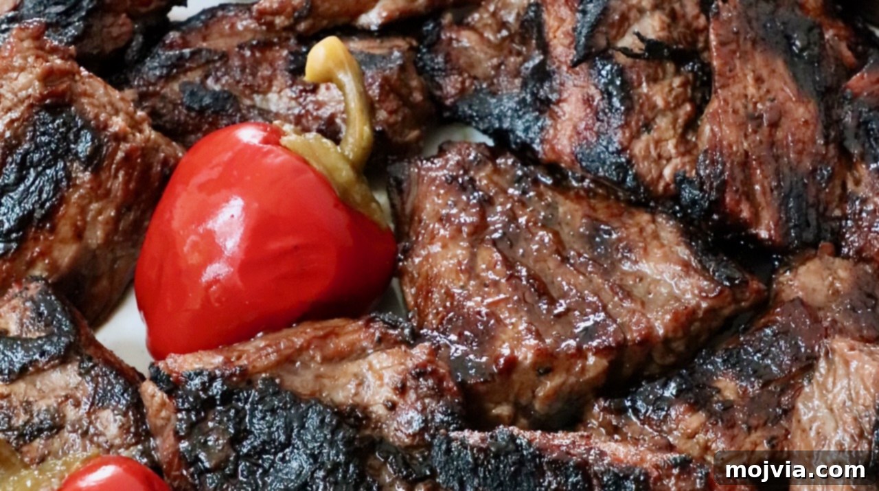 Perfectly grilled steak tips arranged on a plate with vibrant cherry peppers, ready to be enjoyed