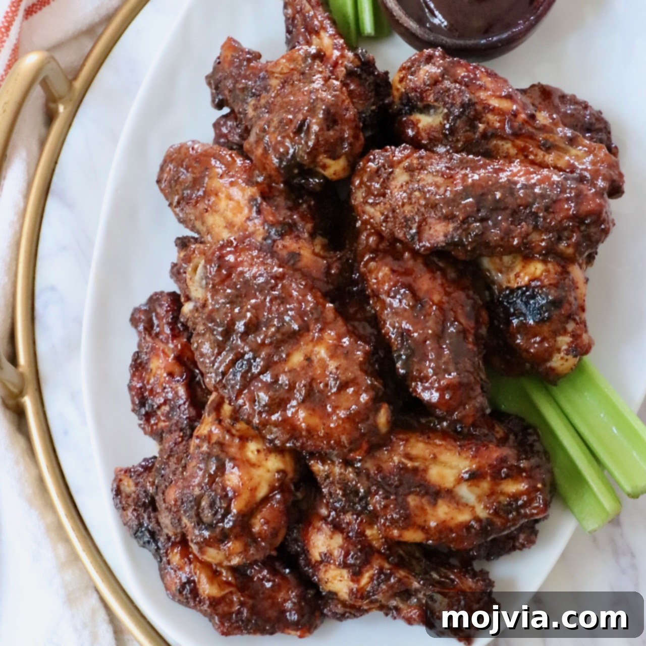 cooked chicken wings tossed in bbq sauce piled up on a plate