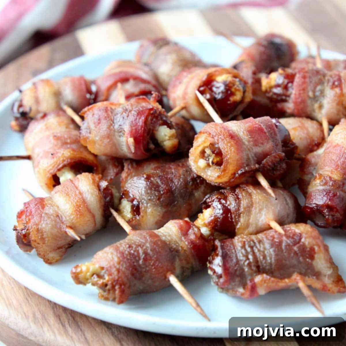 Bacon wrapped dates skewered with toothpicks on white plate
