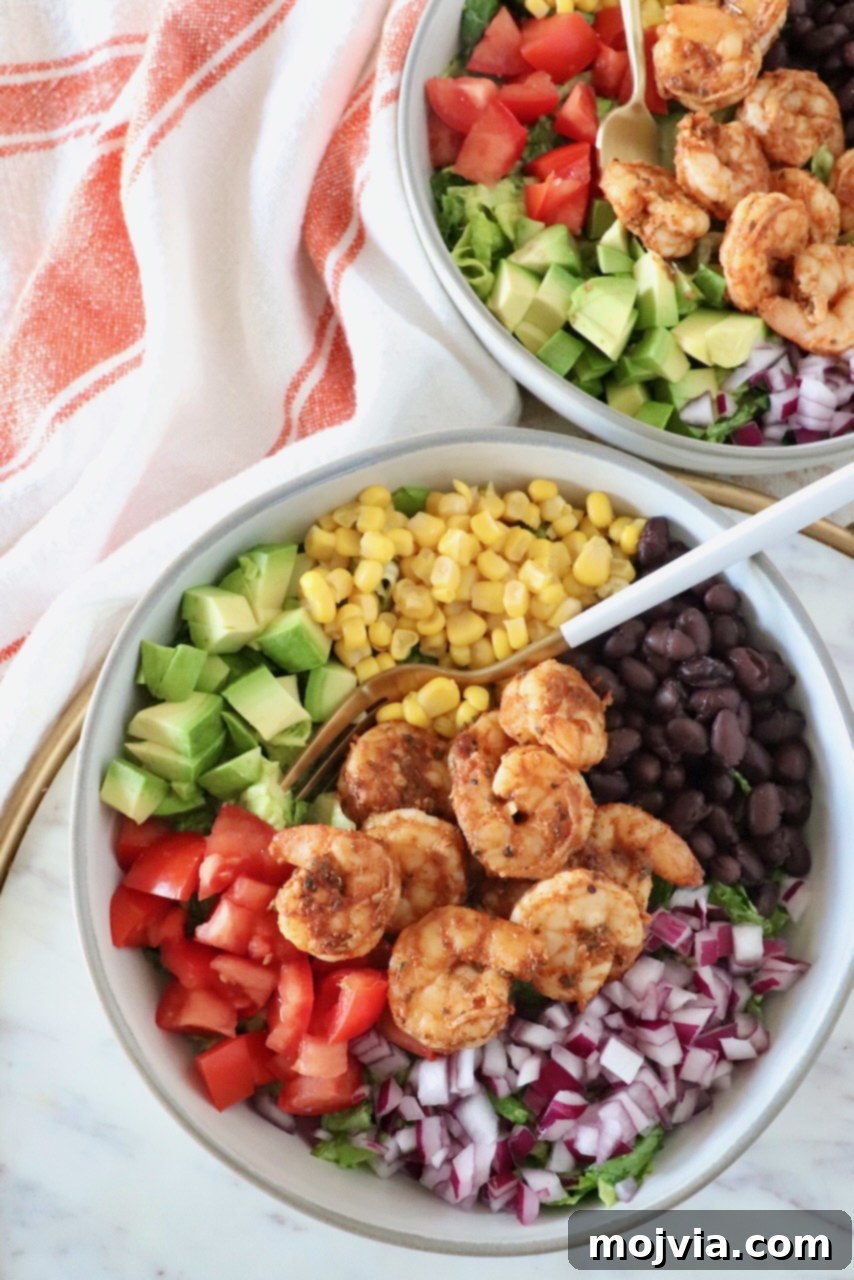 Fresh Fiesta Shrimp Salad 4 A close-up shot of the finished Mexican shrimp salad in a bowl, with a fork ready to enjoy. It showcases succulent shrimp, avocado, red onion, tomato, black beans, and corn.