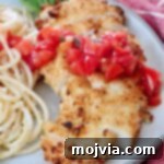 Crispy garlic chicken, sliced and topped with vibrant bruschetta, accompanied by creamy garlic pasta, all ready to serve.