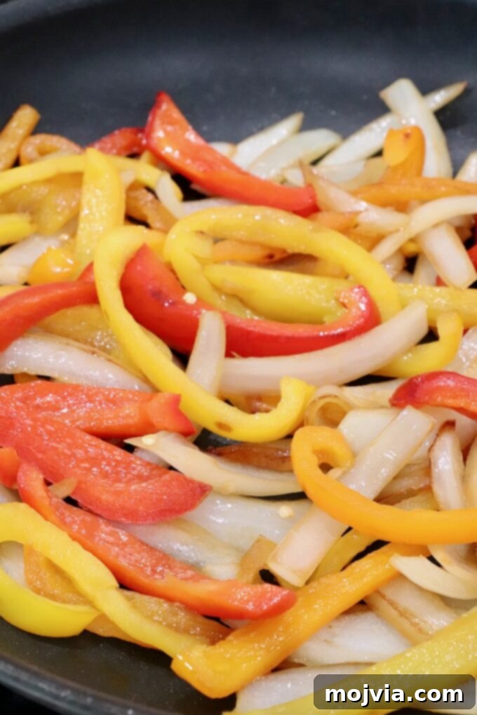 cooked, sliced peppers and onions in a skillet