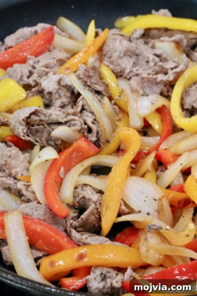 cooked steak, bell peppers, and onions in a skillet