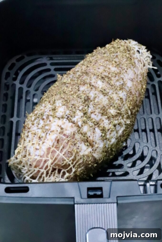 Perfect Air Fried Turkey Breast 5 turkey breast roast wrapped in netting, covered in an herb rub in an air fryer basket