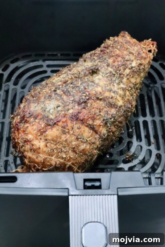 Perfect Air Fried Turkey Breast 6 cooked turkey breast roast wrapped in netting, covered in an herb rub in an air fryer basket