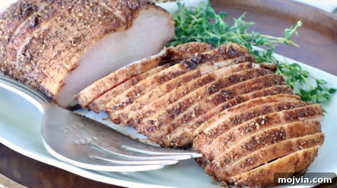 Sliced smoked turkey breast seasoned with spices on a white plate, garnished with fresh thyme. A silver carving fork rests beside it.