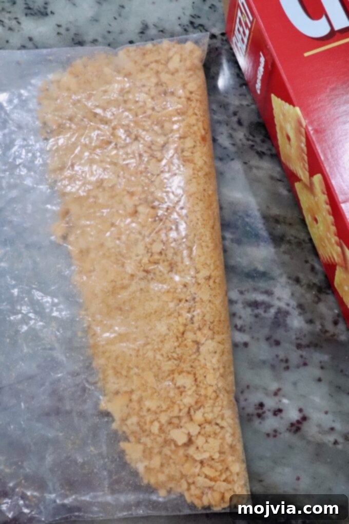 Golden Cheez-It Mac and Cheese Bake 9 Cracker crumbs in a clear plastic bag on a speckled countertop beside a red cracker box