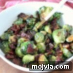 Caramelized Brussels sprouts with crispy bacon pieces in a white bowl with a serving spoon.