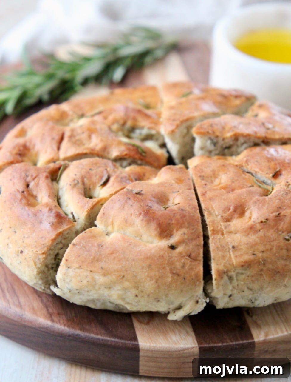 Fragrant Rosemary Focaccia 3 Round focaccia bread cut into diagonal slices on wood cutting board