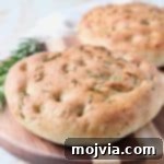 Focaccia Bread on wood cutting board with fresh rosemary sprigs