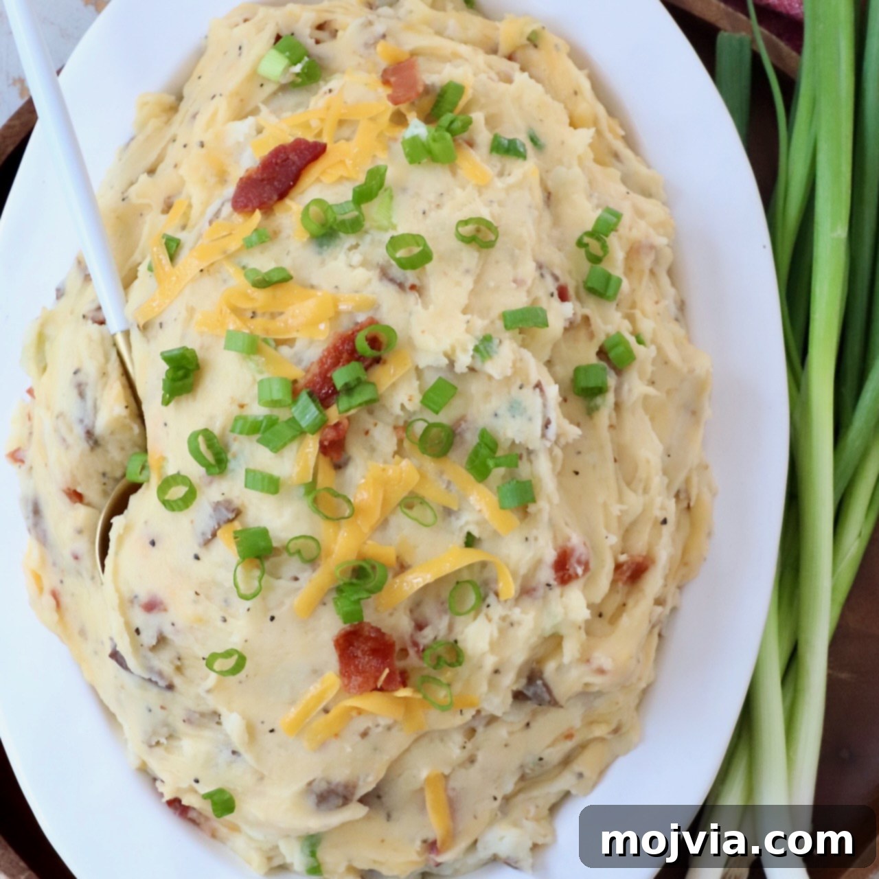 Loaded mashed potatoes in serving dish with spoon