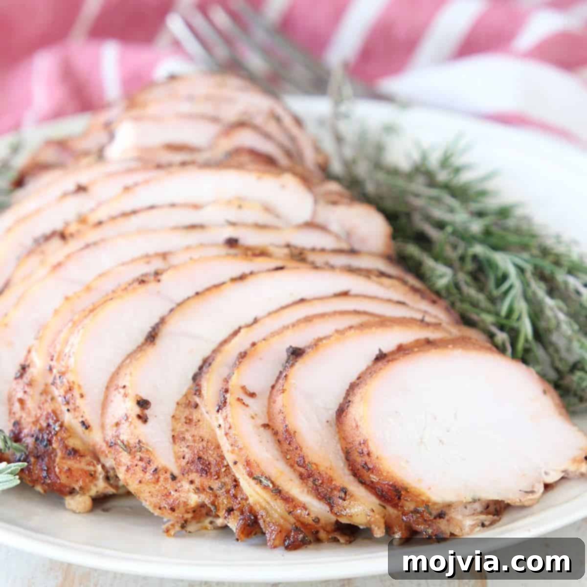 Sliced smoked turkey breast on plate with fresh rosemary and thyme