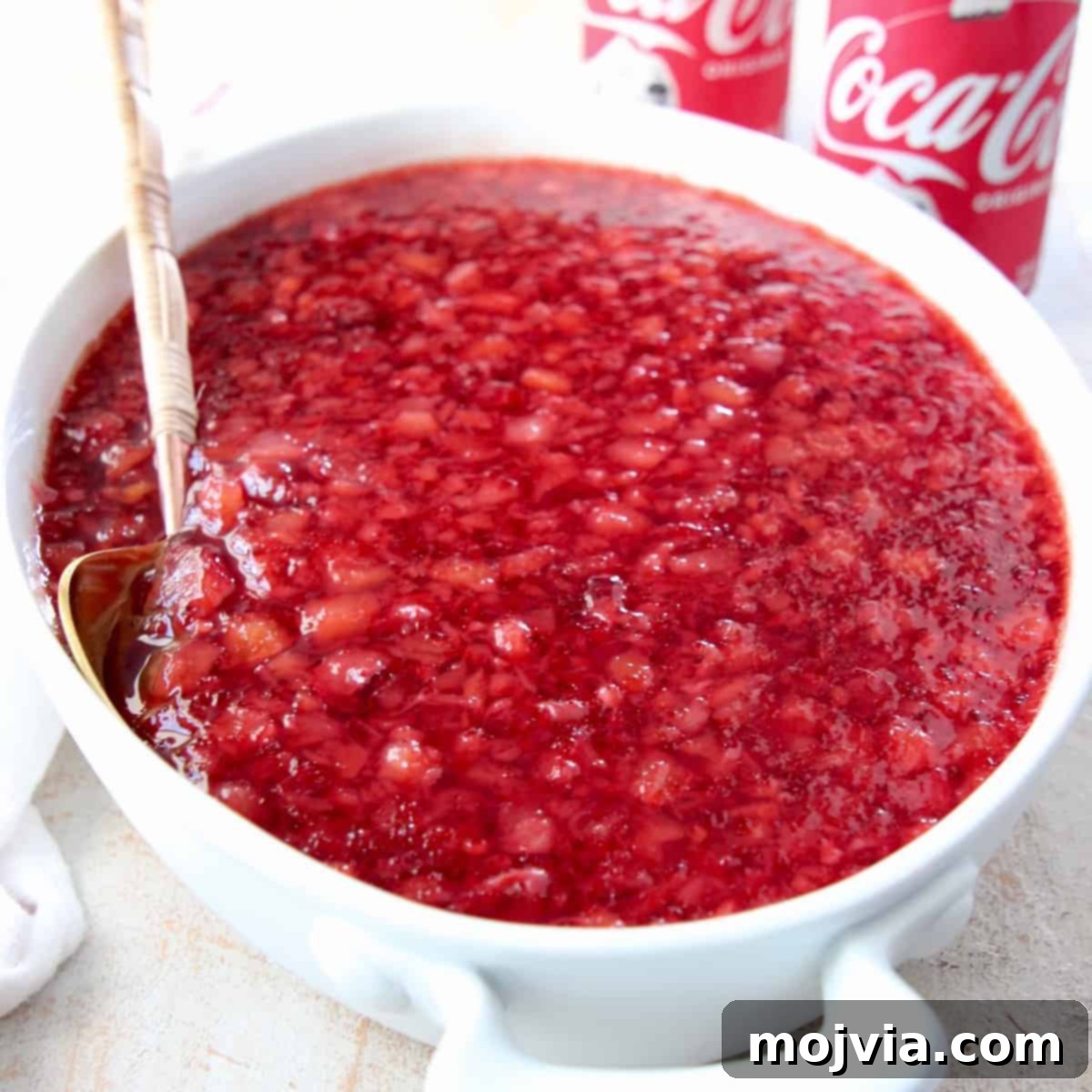 Cherry jello salad in white serving bowl with spoon