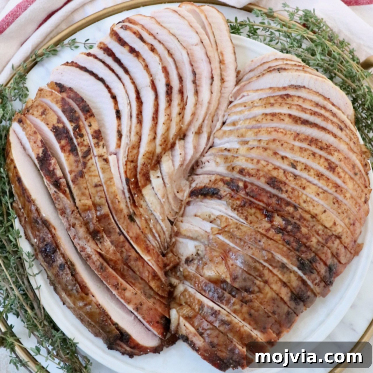 Sliced smoked turkey on a plate with fresh herbs