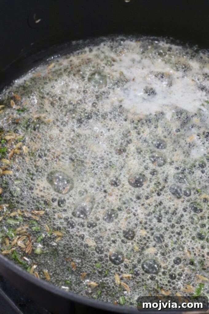 Tender Sirloin Tip Roast 5 Close-up of seeds and herbs simmering in a bubbling, frothy liquid in a black pot