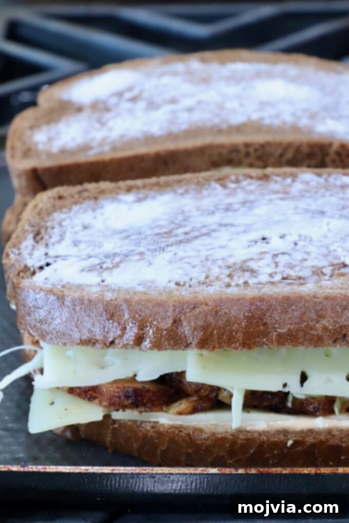 Golden Grilled Turkey Reuben 6 Two sandwiches on a stove. The bread is buttered, with melted cheese and grilled meat peeking out.