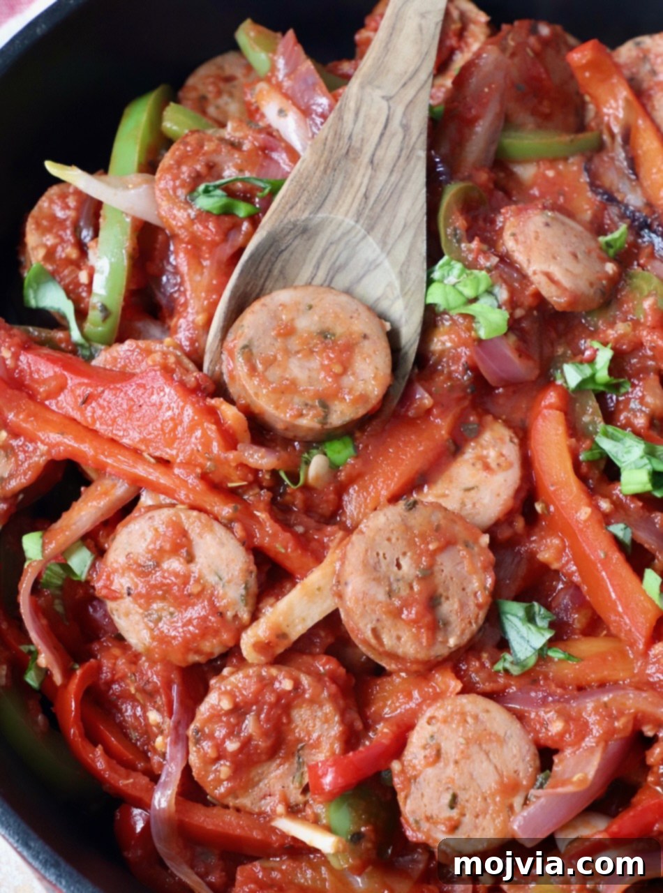 Classic Italian Sausage and Peppers 2 Delicious sliced sausage and colorful bell peppers in a skillet, ready to be served, with a wooden spoon.