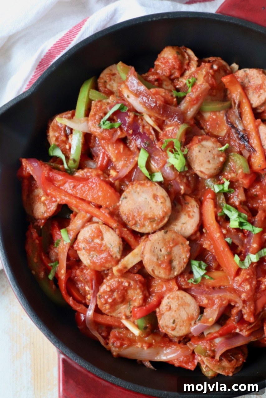 Classic Italian Sausage and Peppers 7 Close-up of sliced sausage and peppers simmering in a rich tomato sauce within a skillet.