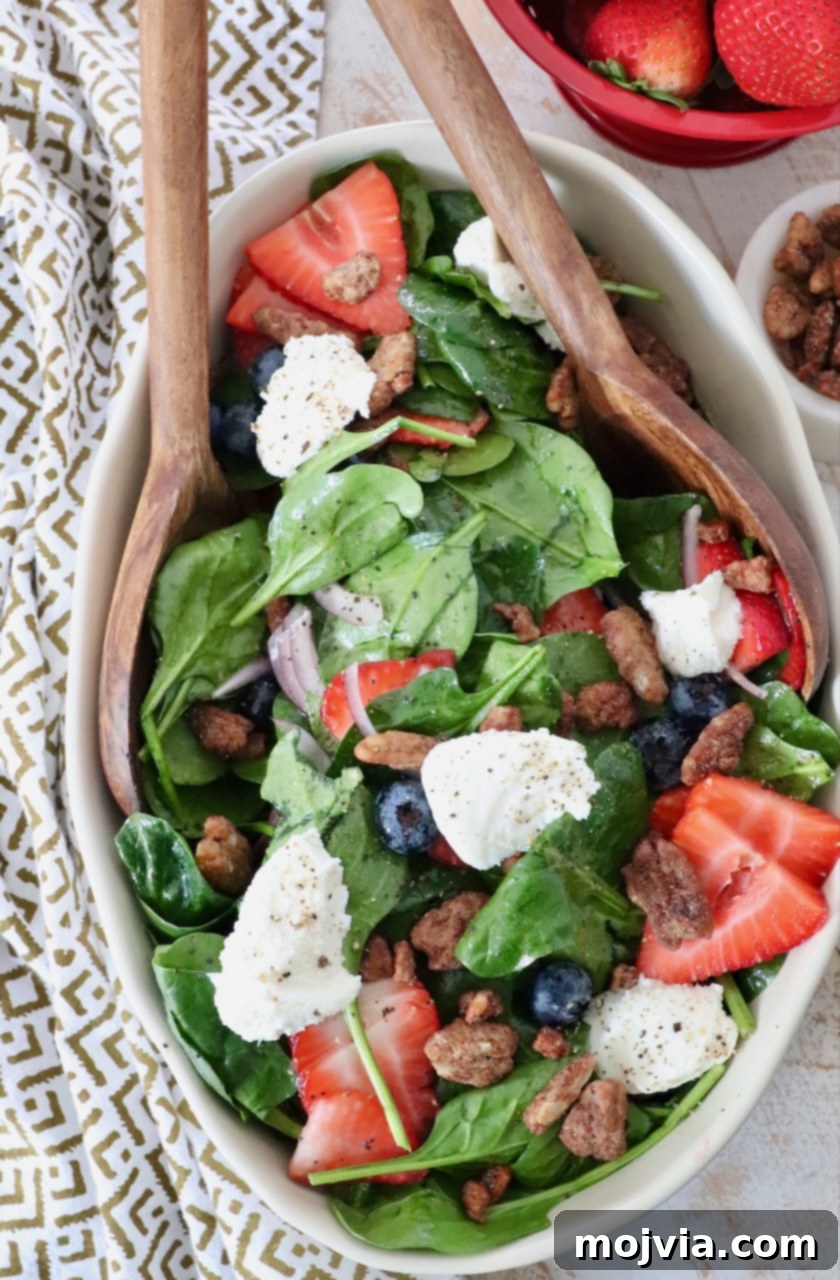 large salad in serving bowl topped with dollops of ricotta cheese and sliced strawberries
