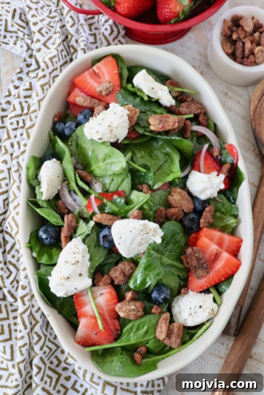 salad in large serving bowl topped with strawberries and ricotta cheese