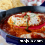 Spatula holding a piece of chicken parmesan with fresh chopped basil