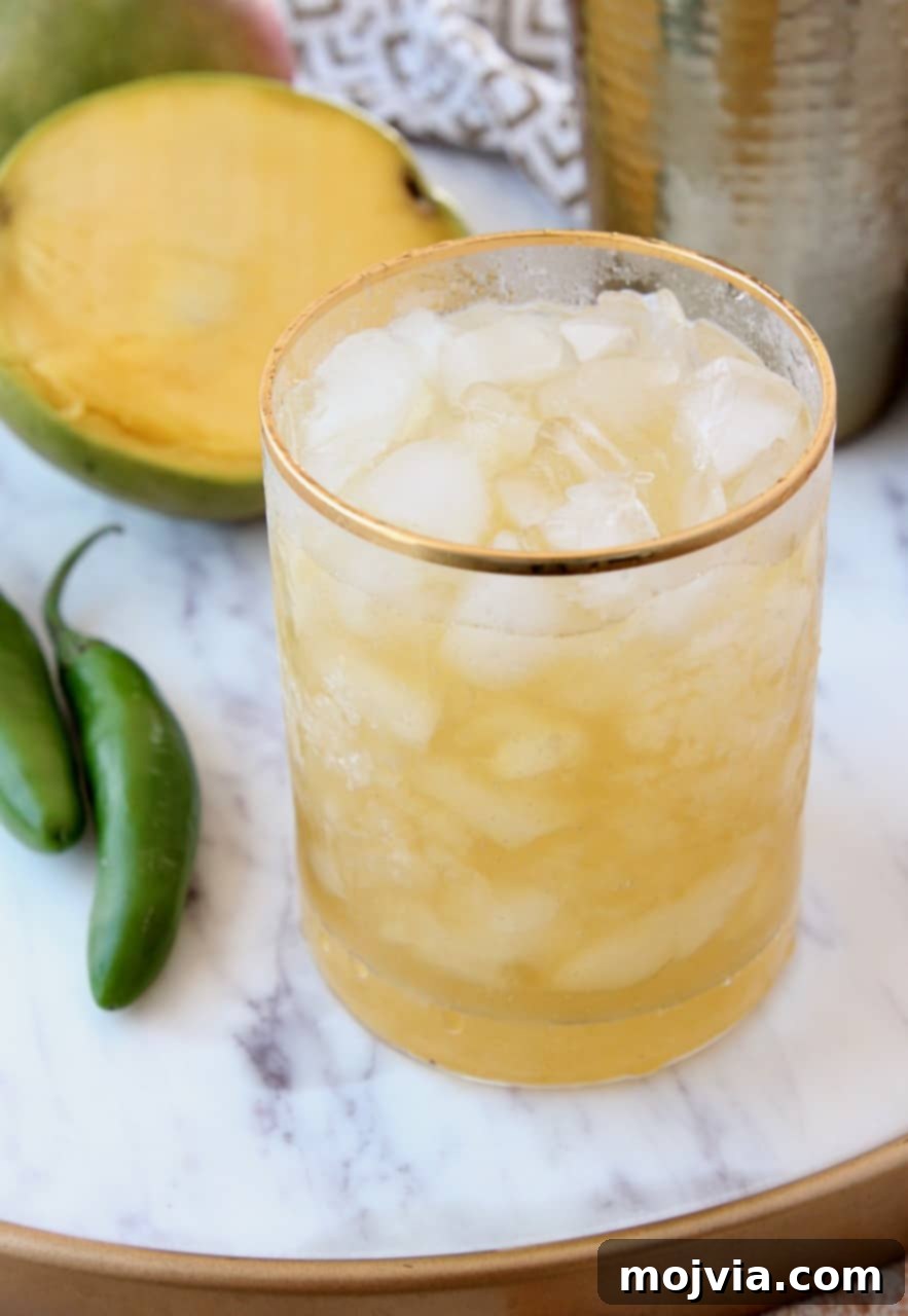 Serrano Mango Margarita Heatwave 5 A beautifully crafted serrano chili mango margarita in a gold-rimmed glass, garnished with a lime wheel and a thin slice of chili.
