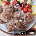 Savory Greek Meatballs with Refreshing Tzatziki 5 Greek meatballs on plate with tomato cucumber salad