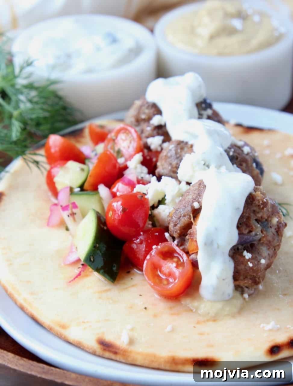 Savory Greek Meatballs with Refreshing Tzatziki 3 Greek meatballs on pita bread with tomato cucumber salad and tzatziki sauce