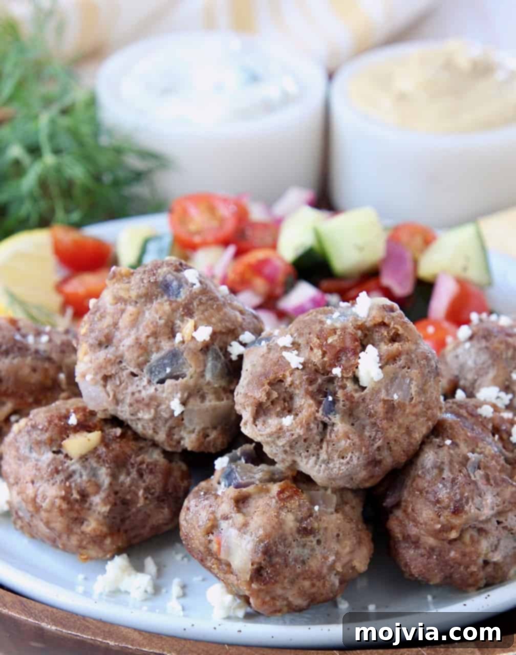 Savory Greek Meatballs with Refreshing Tzatziki 4 Greek meatballs on plate topped with crumbled feta cheese