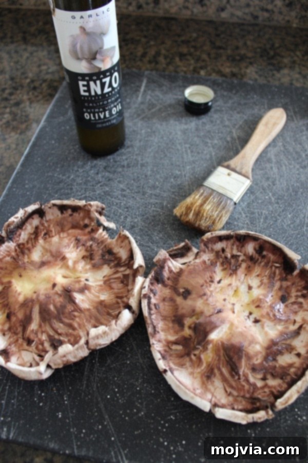 Two large, cleaned portobello mushroom caps on a cutting board, with stems and gills removed, demonstrating proper preparation before stuffing.