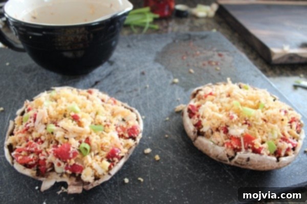 Two portobello mushroom caps generously stuffed with the Mediterranean crab and couscous mixture, neatly arranged on a cutting board, ready for grilling or baking.