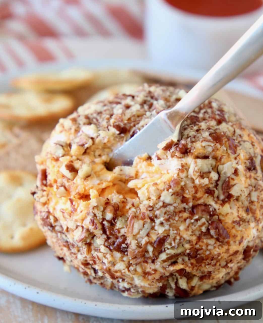Buffalo Kicked Cheddar Cream Cheese Ball 2 A Buffalo Cheddar Cream Cheese Ball with a cheese knife embedded, ready to be served.