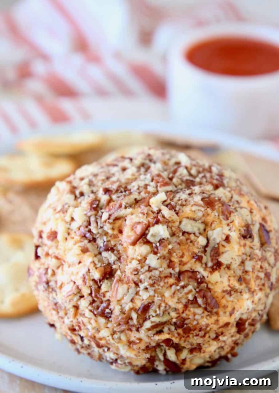Buffalo Kicked Cheddar Cream Cheese Ball 3 A Buffalo Cheddar Cream Cheese Ball rolled in chopped pecans, served on a plate with crackers.