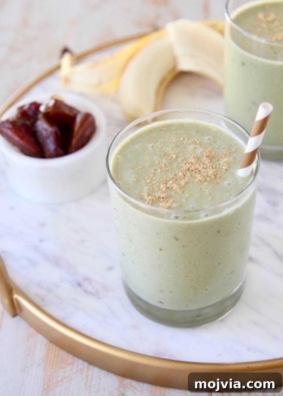 Energizing Banana Date Protein Smoothie 4 Banana protein shake in glass with gold and white striped straw and ground flaxseed on top with peeled banana in background