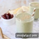Banana protein shakes in glasses with gold and white striped straw and a small bowl of dates in the background
