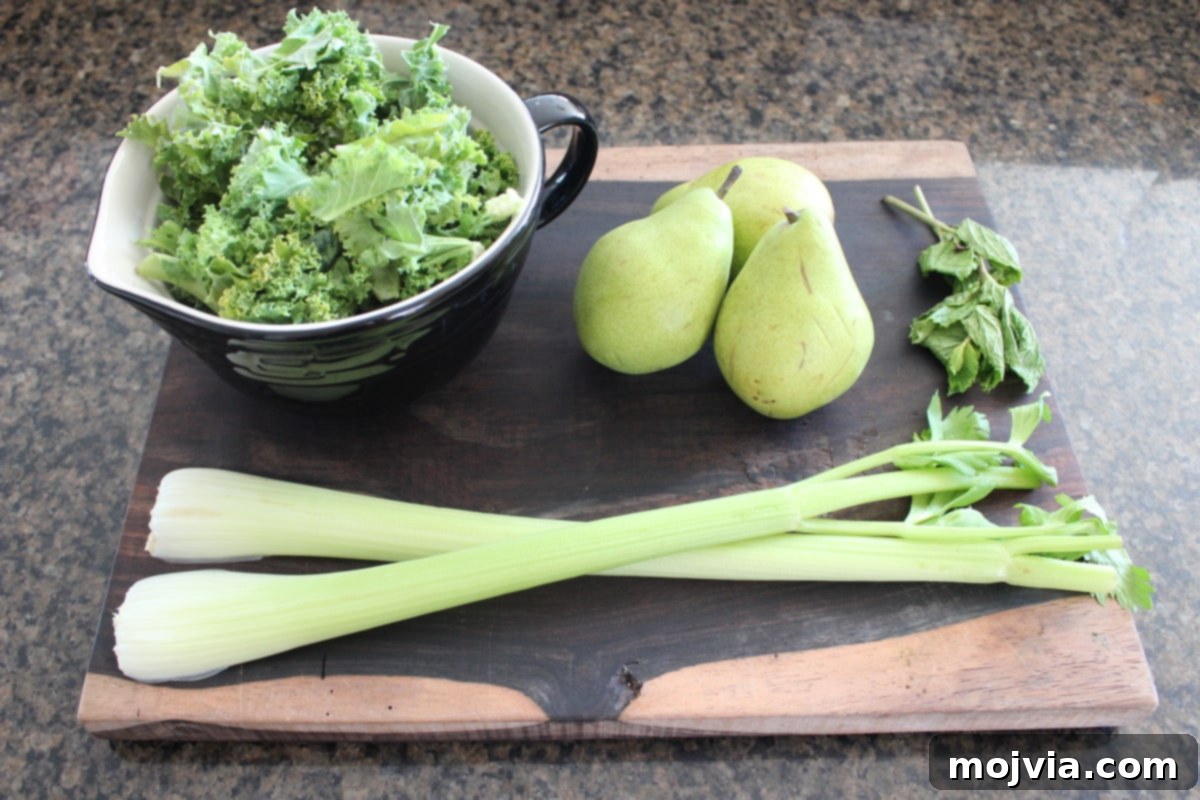 Fresh ingredients laid out for making Celery Pear Green Juice, including celery, pears, kale, and mint.