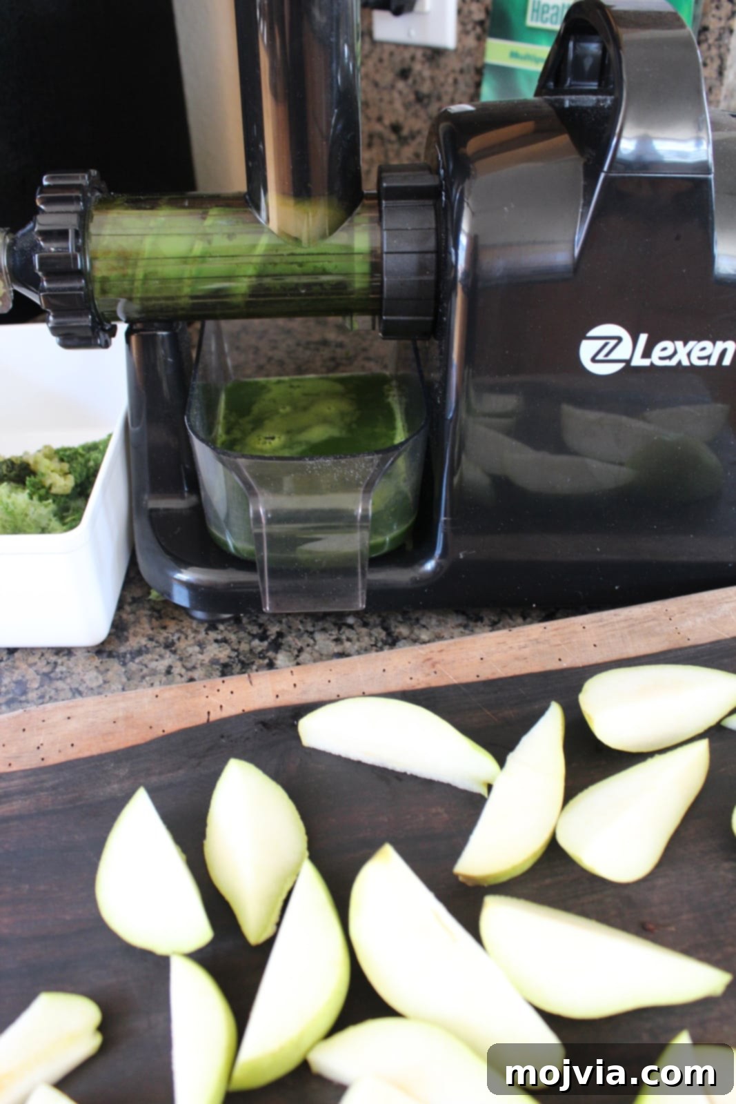 Celery and pears being fed into a juicer to make healthy green juice.