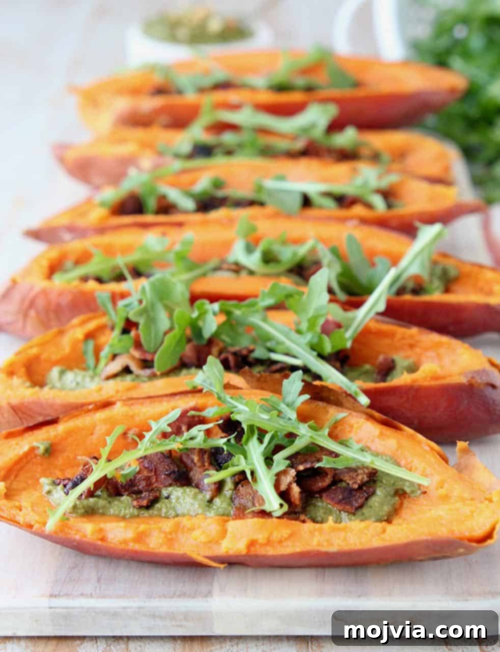 Golden Sweet Potato Skins Topped with Sage Pesto and Crispy Bacon 2 Loaded sweet potato skins on wood serving tray