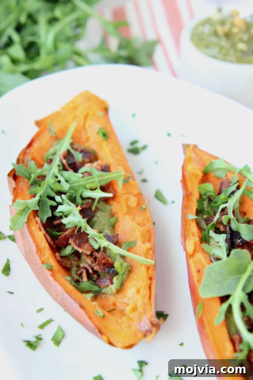 Golden Sweet Potato Skins Topped with Sage Pesto and Crispy Bacon 3 Loaded sweet potato skins with bacon and arugula on white plate