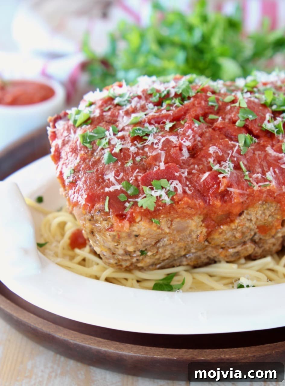 Rustic Italian Meatloaf 4 Italian meatloaf covered in marinara sauce on top of spaghetti in a white bowl