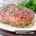 Italian Meatloaf sitting on large bowl of spaghetti noodles with fresh parsley on top